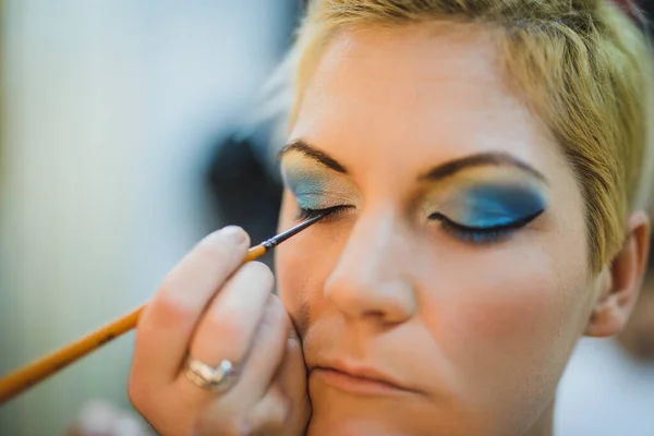 Unrecognizable makeup artist applying eyeshadow on model\'s eye. Close up.