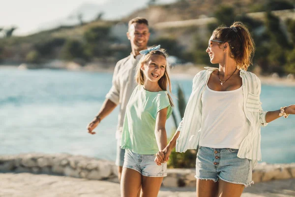 夏休みを楽しみながら海の近くを歩いている笑顔の10代の少女と彼女の両親 — ストック写真