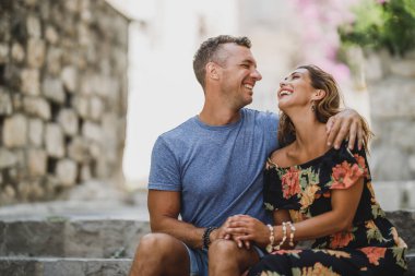 Mutlu çift, Akdeniz 'de merdivenlerde otururken eğleniyor ve tatilin tadını çıkarıyor..