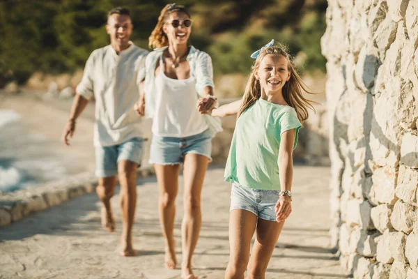 夏休みを楽しみながら海の近くを歩いている笑顔の10代の少女と彼女の両親 — ストック写真