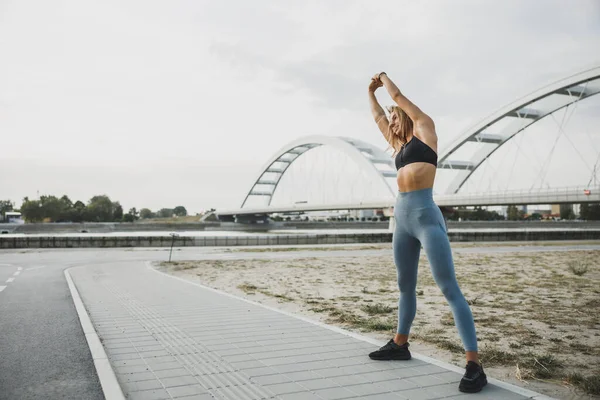 Sportovní Mladá Žena Roztahuje Ruce Při Cvičení Venku Blízkosti Řeky — Stock fotografie