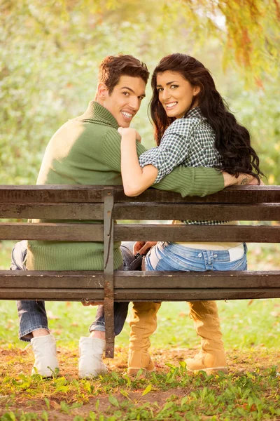 Pareja sonriente joven en un banco del parque — Foto de Stock