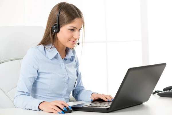 Mujer de negocios con un auricular, escribiendo en el ordenador portátil — Foto de Stock