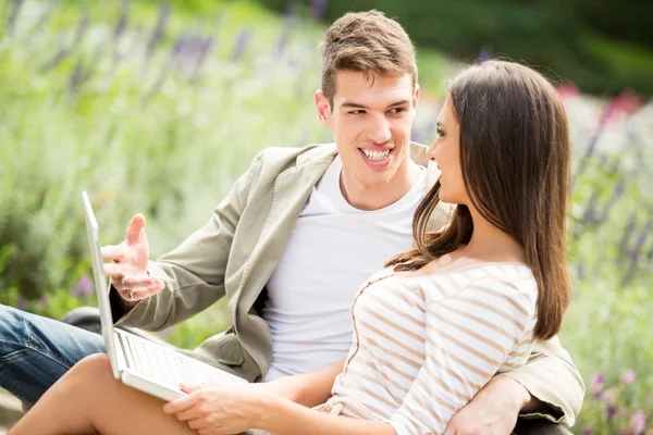 Junges Paar benutzt Laptop im Park — Stockfoto