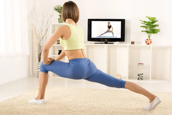 Exercício de mulher bonita na frente da TV — Fotografia de Stock