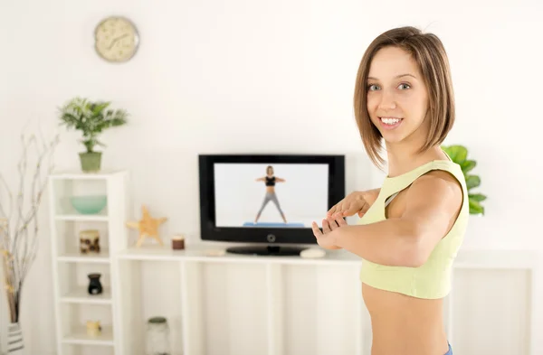 Ejercicio de la mujer delante de la televisión — Foto de Stock