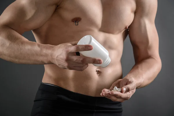 Homem muscular tomando seus comprimidos de suplemento — Fotografia de Stock