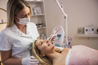 Güzellik uzmanı güzellik salonunda deri kalem kullanan bir müşteri üzerinde kozmetik işlem yapıyor.. 