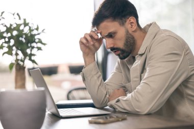 İşadamı evindeki bilgisayarla uğraşırken endişeli görünüyor..