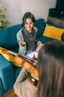 Müzik öğretmeni öğrenciyle keman dersi alırken ona evde keman tutmayı öğretiyor.