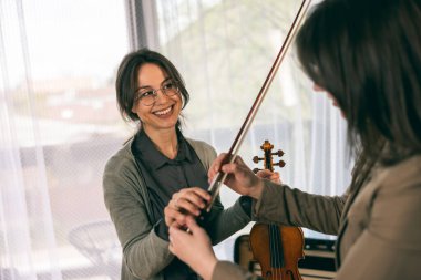 Müzik eğitmeninin öğrenciyle özel keman dersi var ve ona keman tutmayı öğretiyor.. 