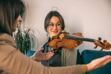 Müzik öğretmeni, özel derste öğrencisine keman tutmayı öğretiyor.. 