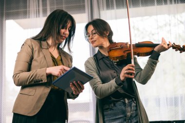 Müzik eğitmeninin öğrenciyle özel keman dersi var ve ona keman tutmayı öğretiyor.. 