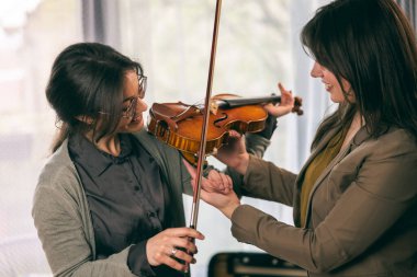 Müzik eğitmeninin öğrenciyle özel keman dersi var ve ona keman tutmayı öğretiyor.. 