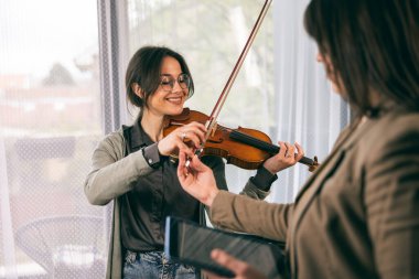 Müzik öğretmeni keman çalmayı öğrenen öğrencisine parmaklarını nasıl tutacağını anlatıyor.. 