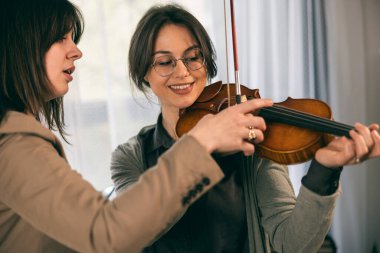 Müzik eğitmeninin öğrenciyle özel keman dersi var ve ona keman tutmayı öğretiyor.. 