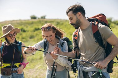 Üç arkadaş güzel bir bahar gününde sırt çantaları ve yürüyüş direkleriyle yürüyüş yapıyor.. 