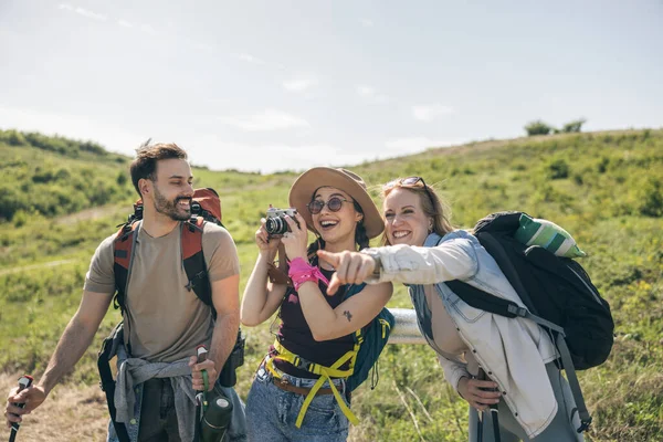 Üç mutlu arkadaş doğa yürüyüşü yaparken ve kamerayla fotoğraf çekerken eğleniyorlar.. 