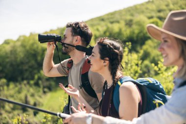 Mutlu arkadaşlar güneşli bir günde yürüyüş yaparken dürbünle kırları keşfediyorlar.. 
