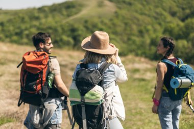 Güler yüzlü arkadaşlar, güneşli bir günde kırsalda yürüyüş yaparken eğleniyorlar.. 
