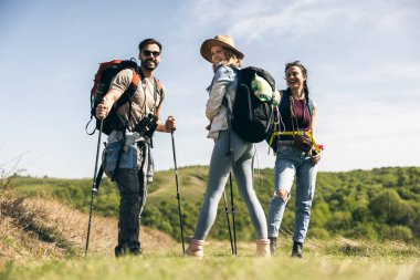 Güler yüzlü arkadaşlar, güneşli bir günde kırsalda yürüyüş yaparken eğleniyorlar.. 