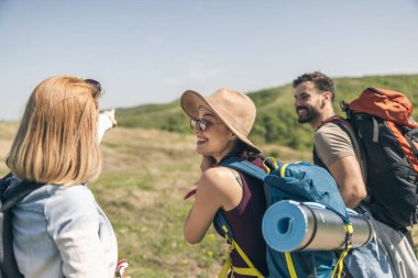 Üç mutlu arkadaş doğa yürüyüşü yaparken ve kamerayla fotoğraf çekerken eğleniyorlar..