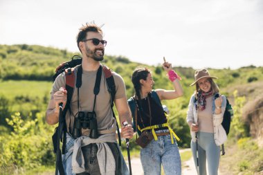 Üç mutlu ve neşeli arkadaş doğada birlikte yürüyüp yürüyorlar..
