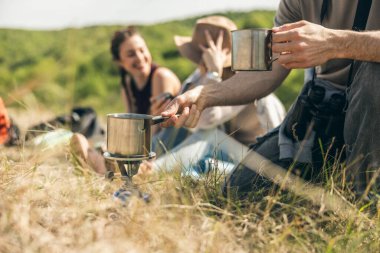 Güneşli bir günde kırsalda yürüyüş yapan arkadaşlar piknik yapıyor..