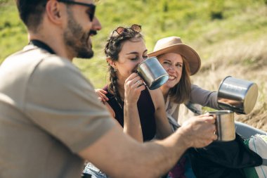 Güneşli bir günde kırsalda yürüyüş yapan arkadaşlar piknik yapıyor..