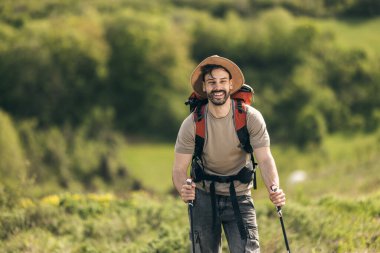 Güneşli bir günde dağlarda yürüyüş yapan mutlu genç adam..