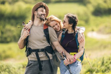 Arkadaşlar güneşli bir günde yürüyüş yaparken ve gülerken doğada birlikte vakit geçirmenin keyfini çıkarıyorlar..