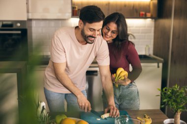 Mutlu, neşeli bir çift meyve hazırlıyor ve muzları birleştiriyor..