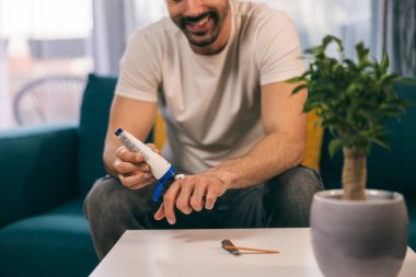 Gülümseyen adam evde otururken eline losyon sürüyor..