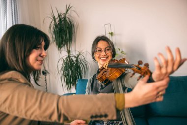 Müzik öğretmeni, özel derste öğrencisine keman tutmayı öğretiyor..