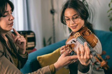 Müzik öğretmeni, özel derste öğrencisine keman tutmayı öğretiyor..