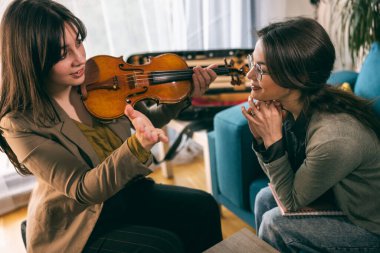 Kemanı tutan ve öğrencisine evde nasıl yapılacağını öğreten müzik öğretmeni..