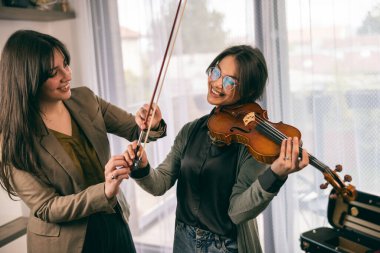 Müzik eğitmeninin öğrenciyle özel keman dersi var ve ona keman tutmayı öğretiyor..