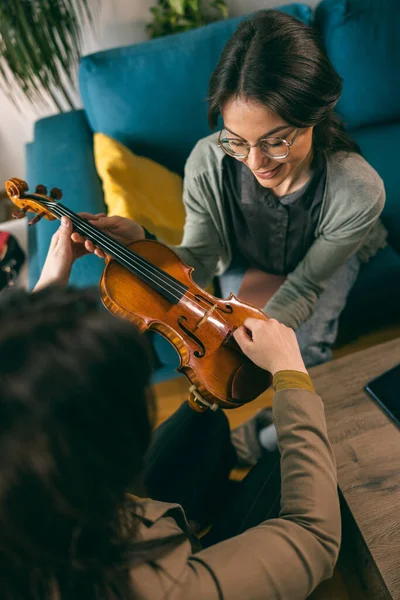 Kemanı tutan ve öğrencisine evde nasıl yapılacağını öğreten müzik öğretmeni..