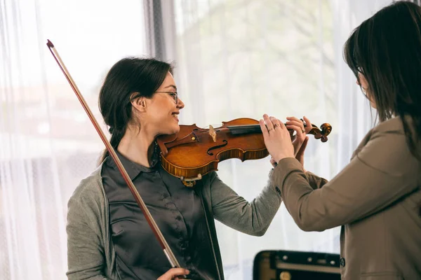 Müzik eğitmeninin öğrenciyle özel keman dersi var ve ona keman tutmayı öğretiyor..