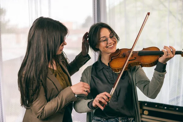 Müzik eğitmeninin öğrenciyle özel keman dersi var ve ona keman tutmayı öğretiyor..