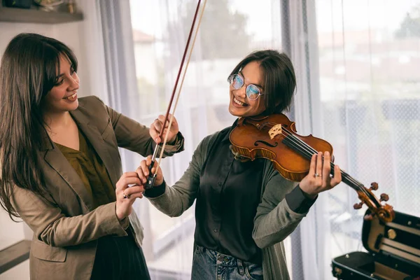 Müzik eğitmeninin öğrenciyle özel keman dersi var ve ona keman tutmayı öğretiyor..