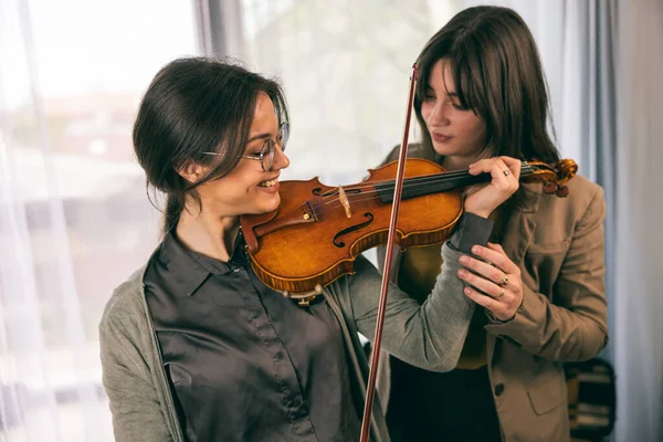 Müzik öğretmeni, öğrencisine evde keman çalmayı öğretiyor..