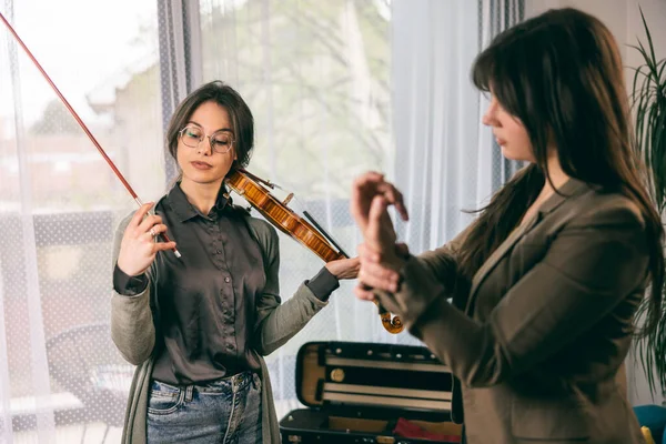 Müzik öğretmeni keman çalmayı öğrenen öğrencisine parmaklarını nasıl tutacağını anlatıyor..