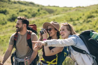 Üç mutlu arkadaş doğa yürüyüşü yaparken ve kamerayla fotoğraf çekerken eğleniyorlar..