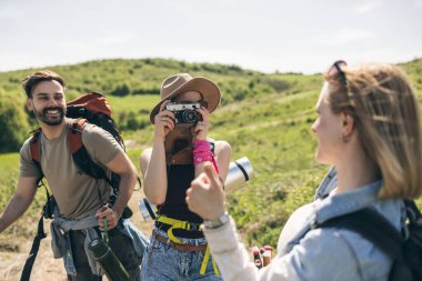 Üç mutlu arkadaş doğa yürüyüşü yaparken ve kamerayla fotoğraf çekerken eğleniyorlar..