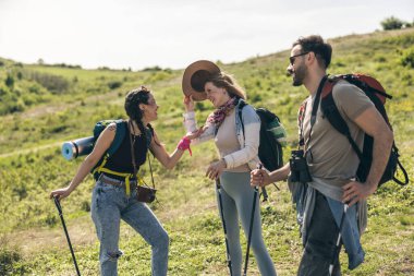 Güler yüzlü arkadaşlar, güneşli bir günde kırsalda yürüyüş yaparken eğleniyorlar..