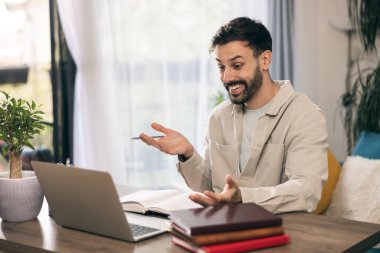 Genç adam evde dizüstü bilgisayarla videolar üzerinde çalışıyor..