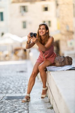 Yabancı bir şehri keşfederken gülümseyen genç bir kadının fotoğrafı..