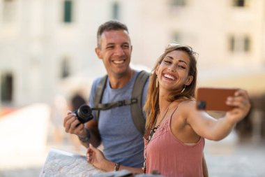 Gülümseyen çift yaz tatilinin tadını çıkarırken Akdeniz şehrinde merdivenlerde oturmuş şehir haritasını inceliyor..