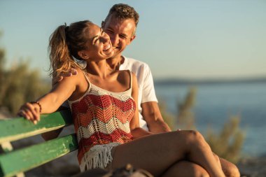 Sevgi dolu bir çift bankta oturuyor ve deniz kıyısında yaz tatilinin tadını çıkarıyorlar..